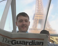 Paul reading the Guardian International Edition on a boat by the Eiffel Tower